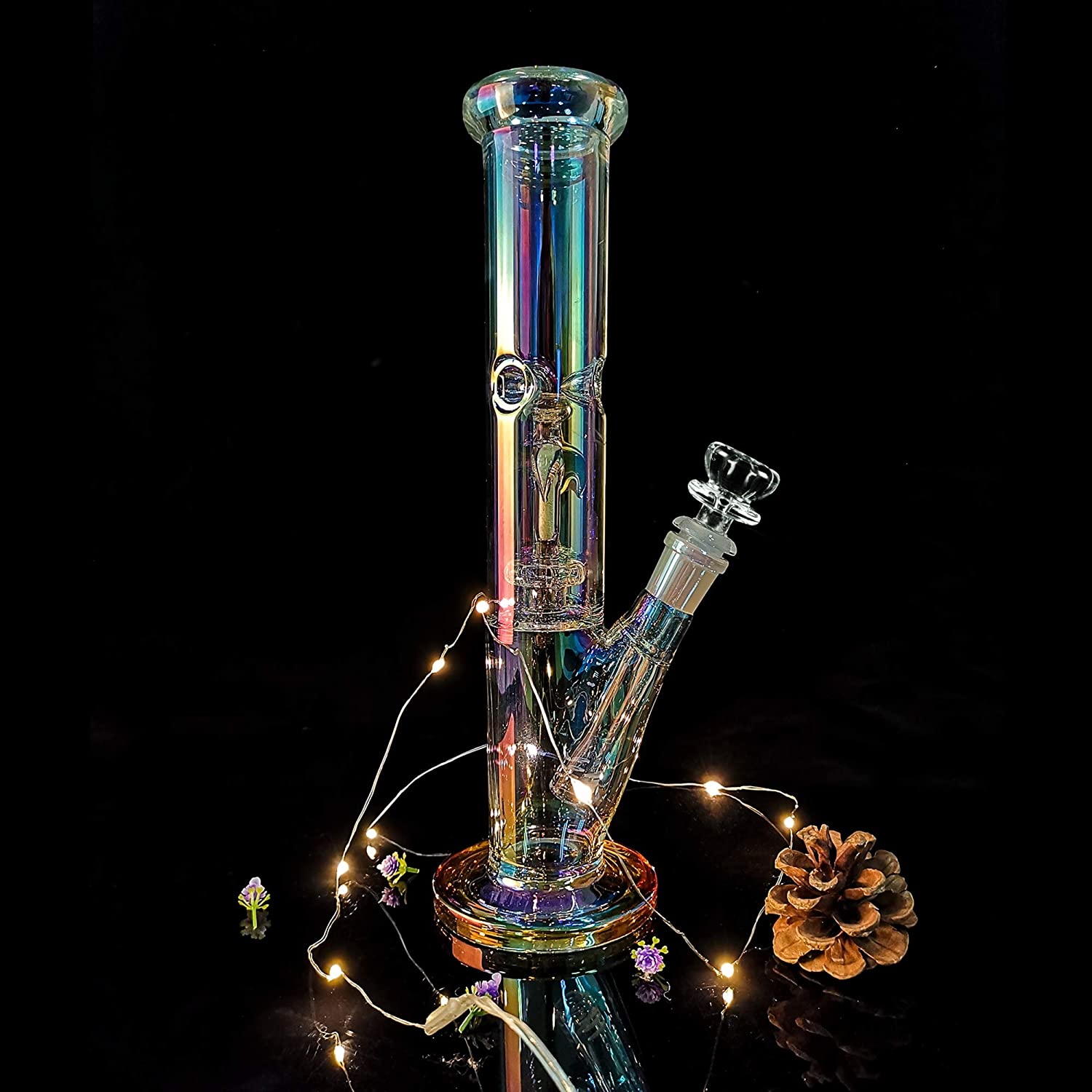 Glow in the dark straight tube bong styled with fairy lights on a reflective black surface