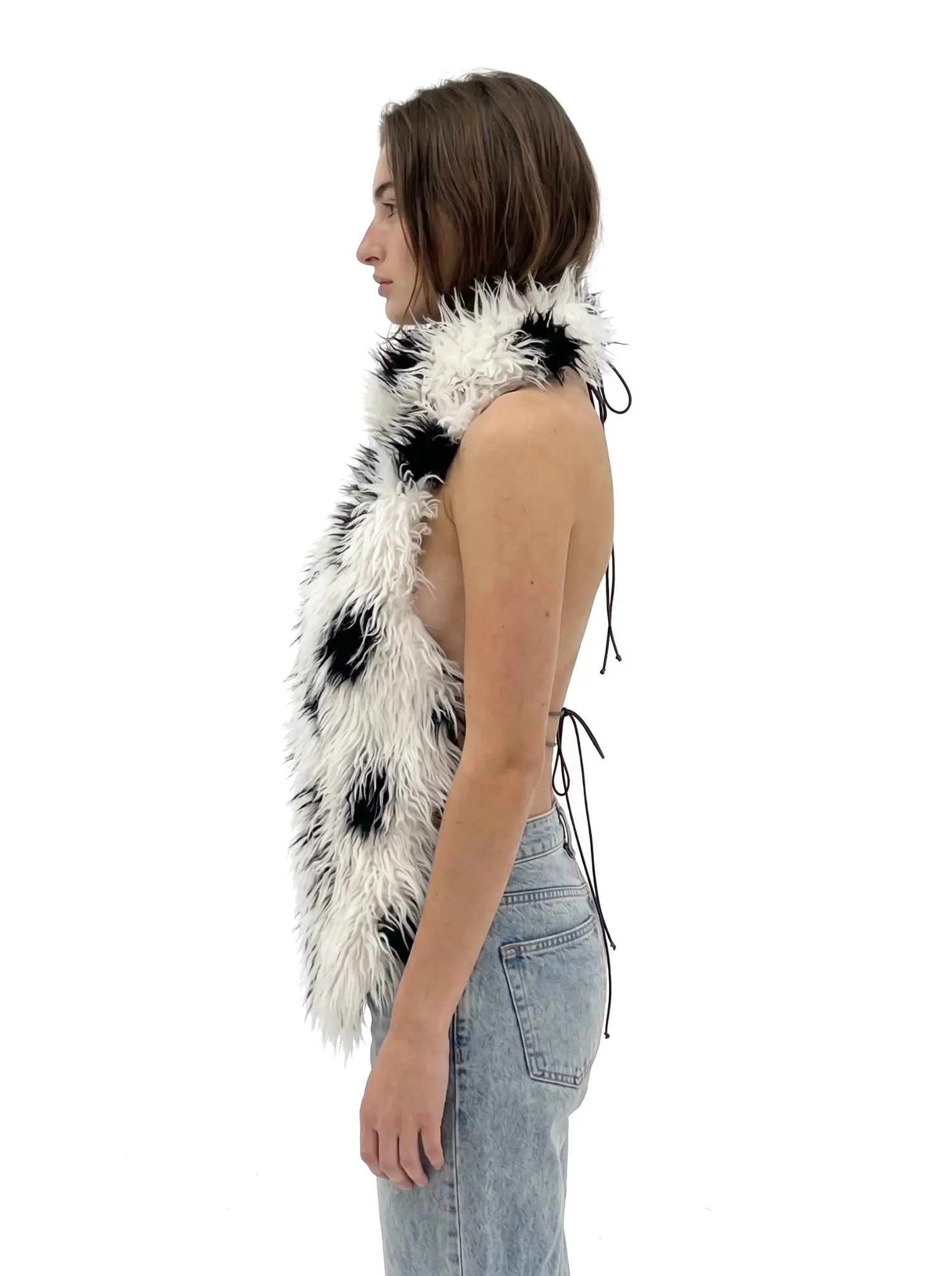 Three-quarter side-back view of a woman wearing a spotted faux fur vest