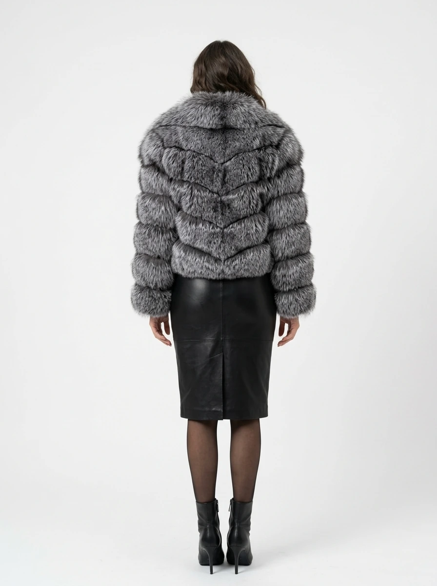 Back view of a charcoal gray short faux fur jacket showing horizontal panels and long sleeves