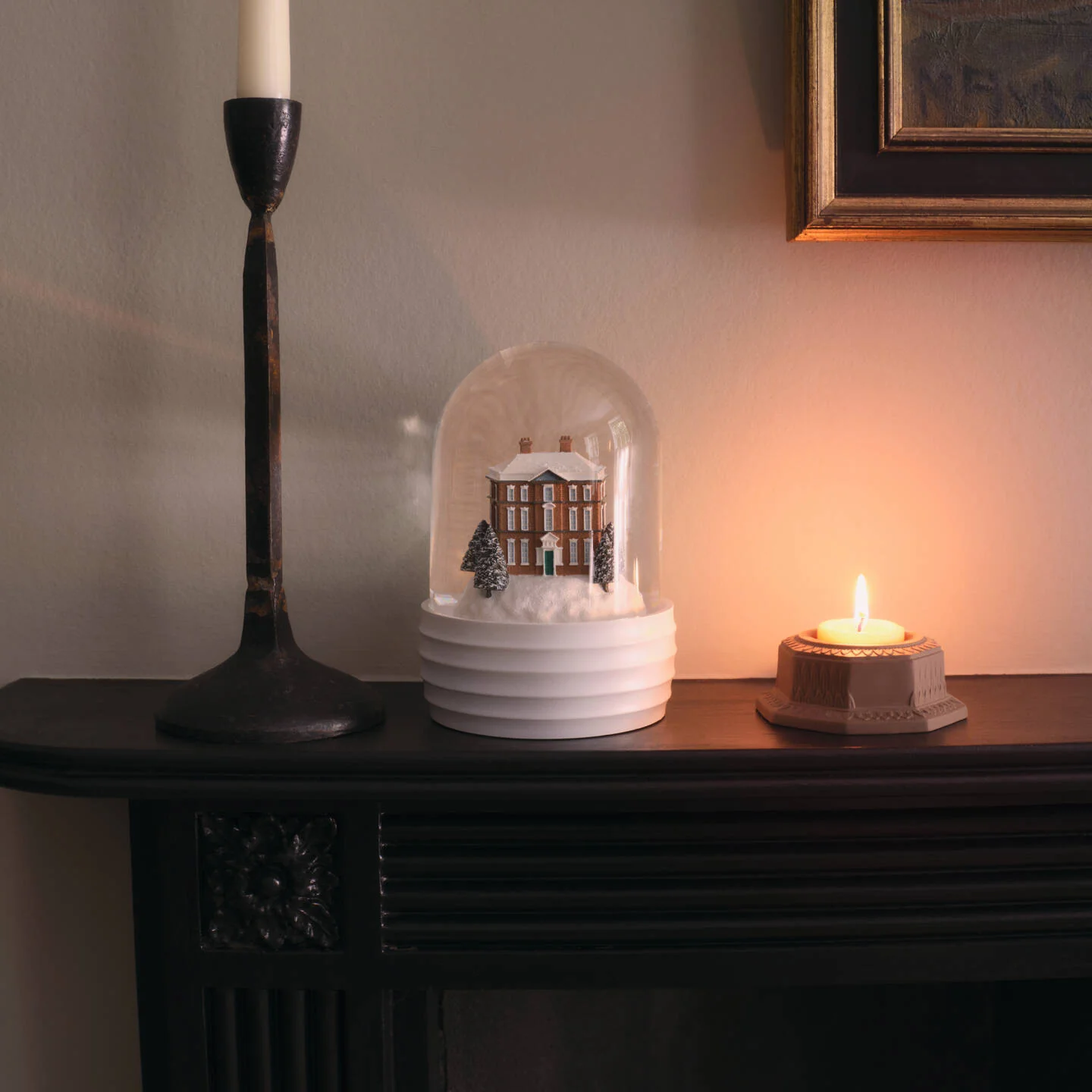 Tealight Holder Jasper Marsh Green - A white ceramic Wedgwood house snow globe under a clear dome sits on a dark mantel beside a lit candle holder and a tall candle, against a warm-toned wall.
