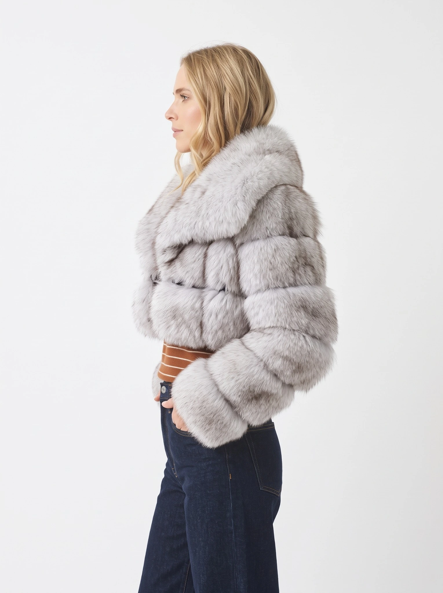 Side view of a woman wearing a gray short faux fur jacket with a wide collar and blue jeans