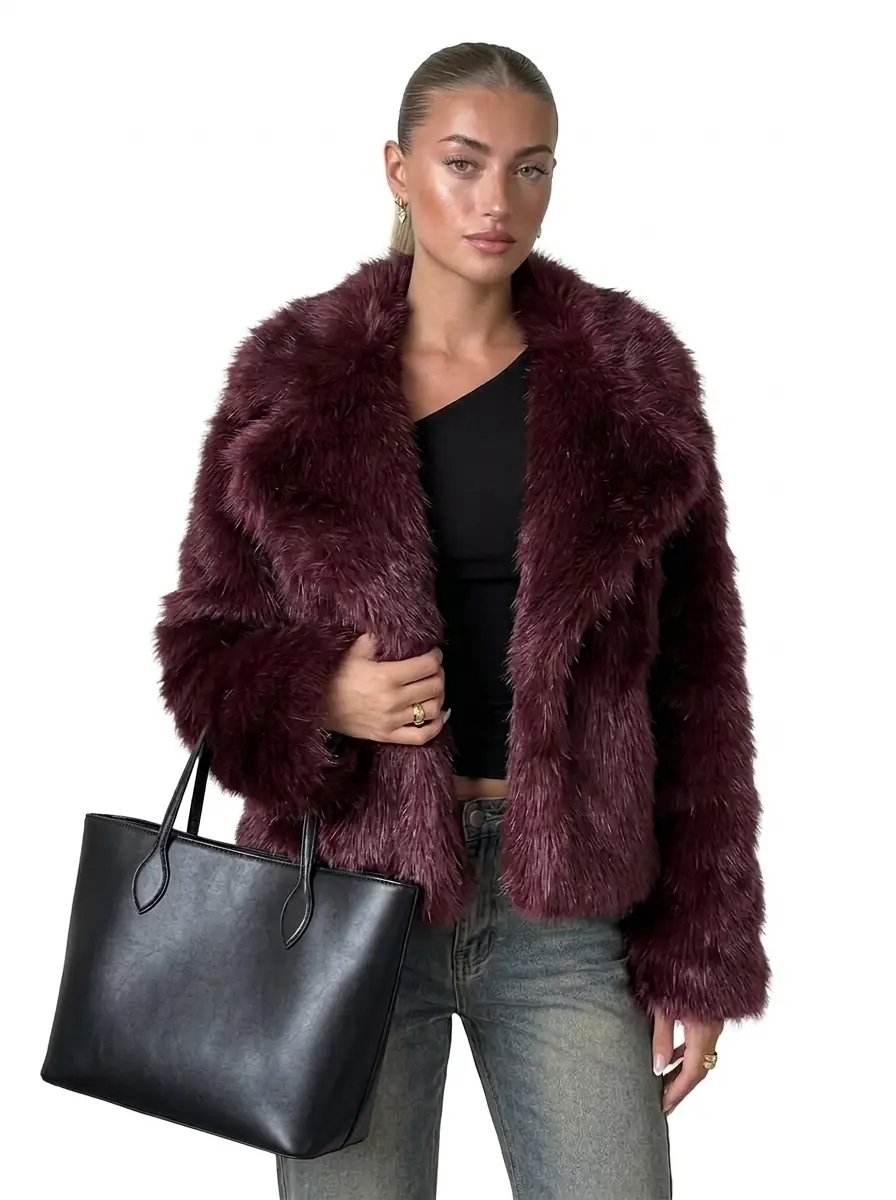 Woman modeling a maroon faux fur jacket with a black handbag