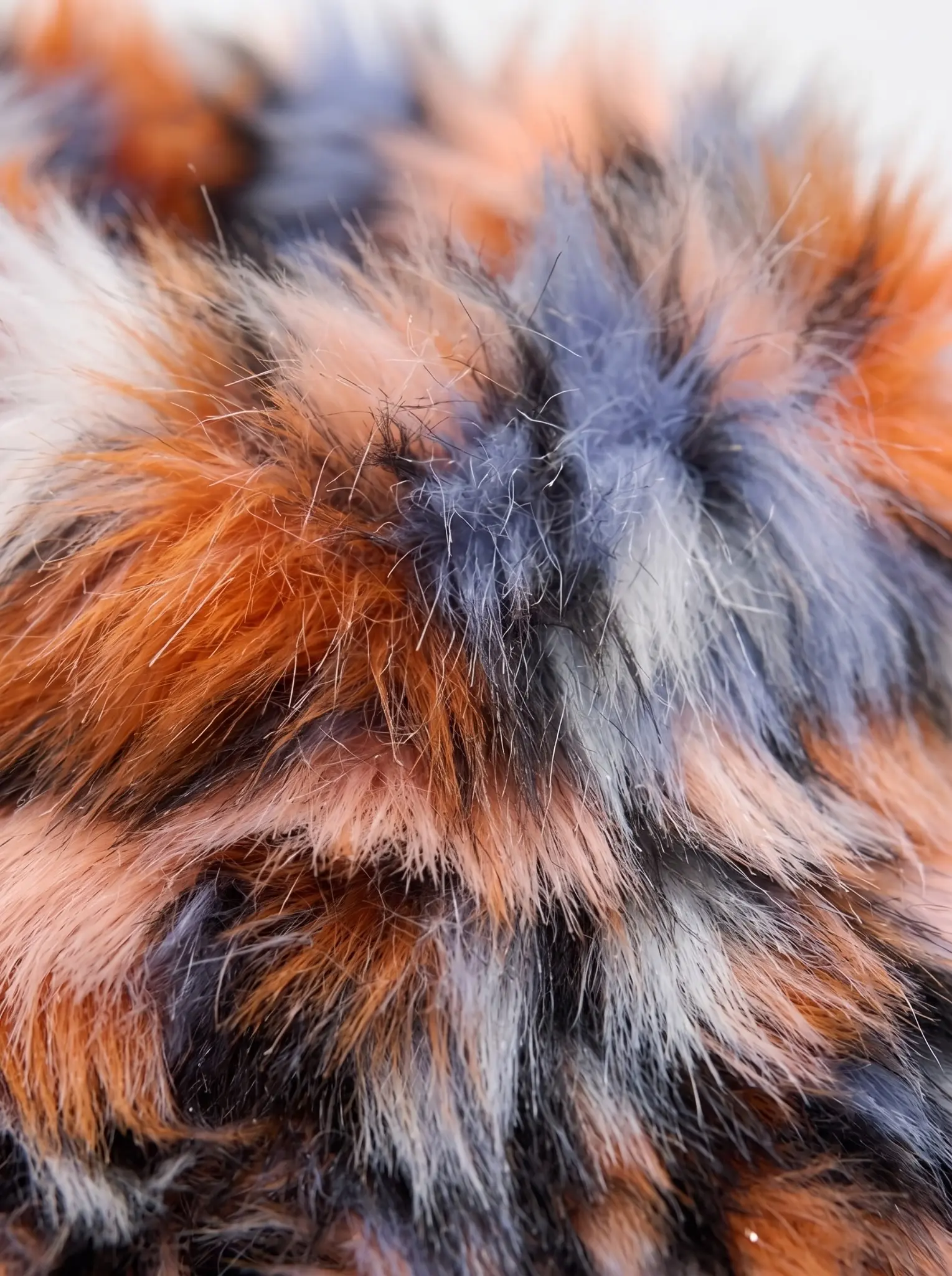 Close-up of the orange, blue, and peach spotted faux fur texture