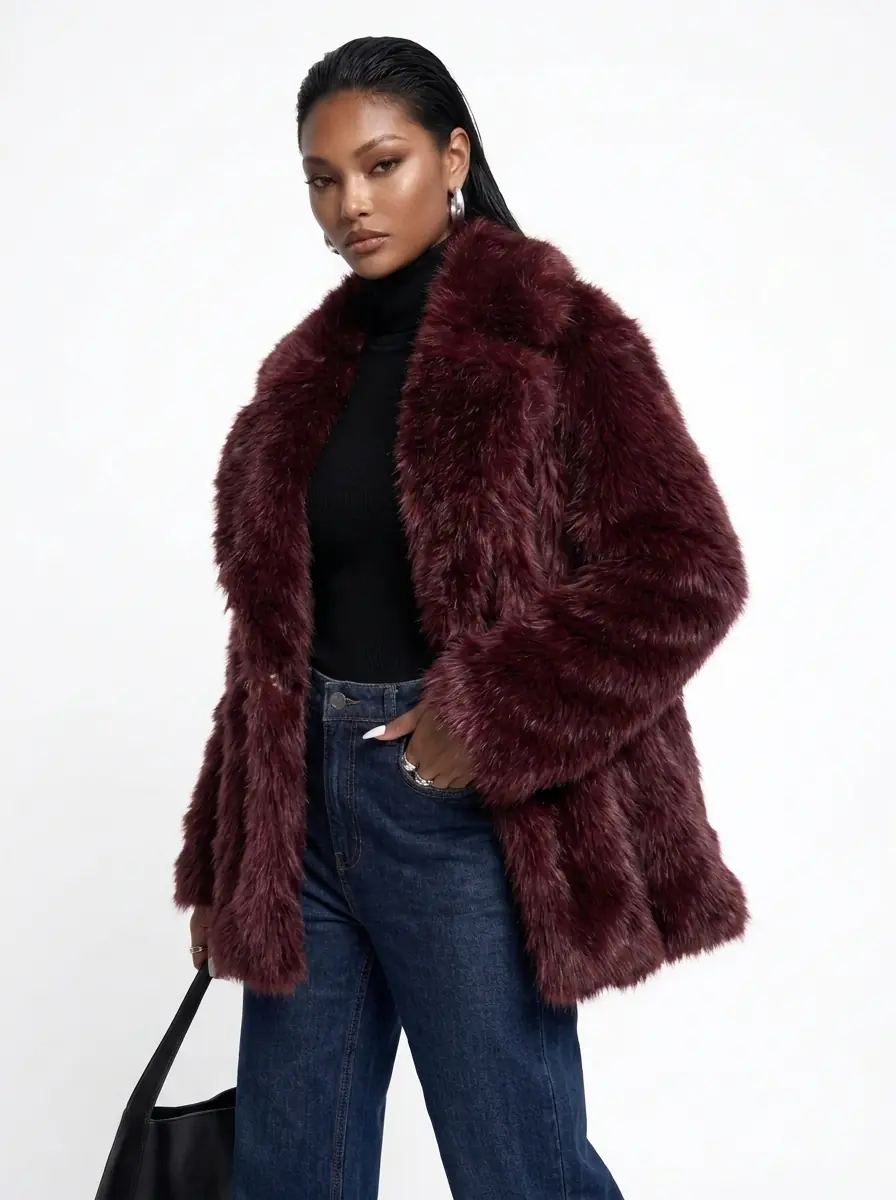 Woman modeling a burgundy faux fur coat with blue jeans