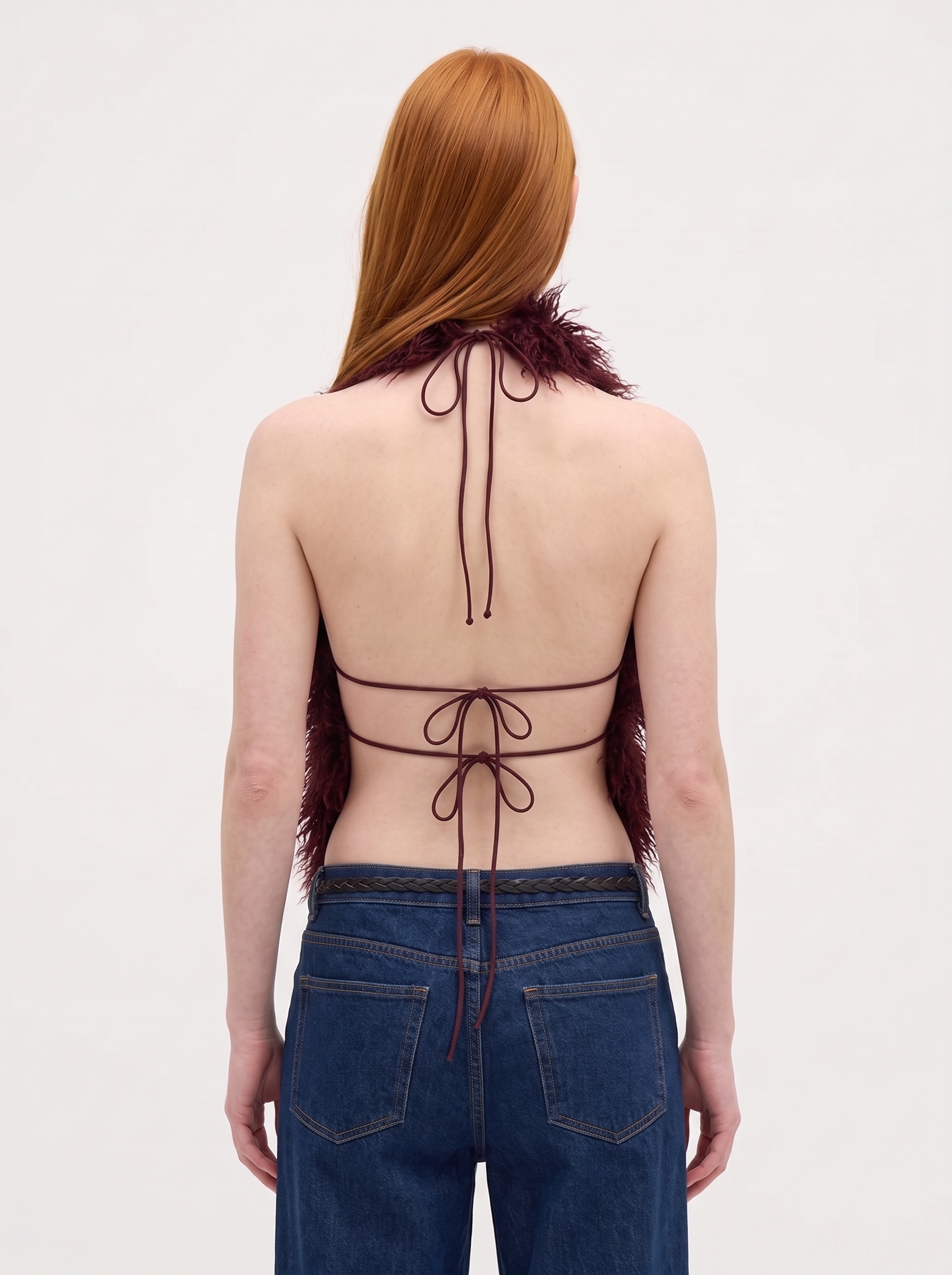 Back view of a woman wearing a maroon faux fur halter vest with an open back and tie straps