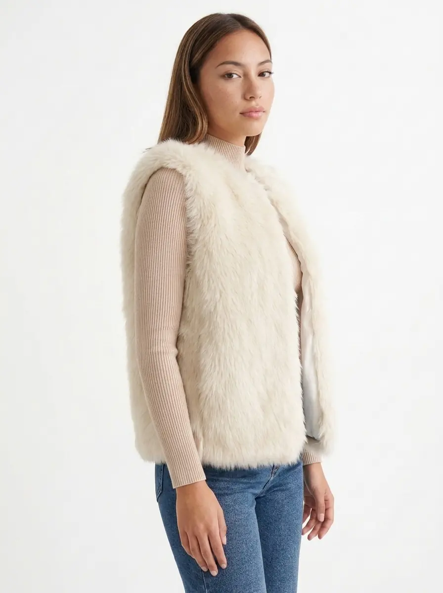 Woman wearing a cream faux fur vest in a three-quarter view