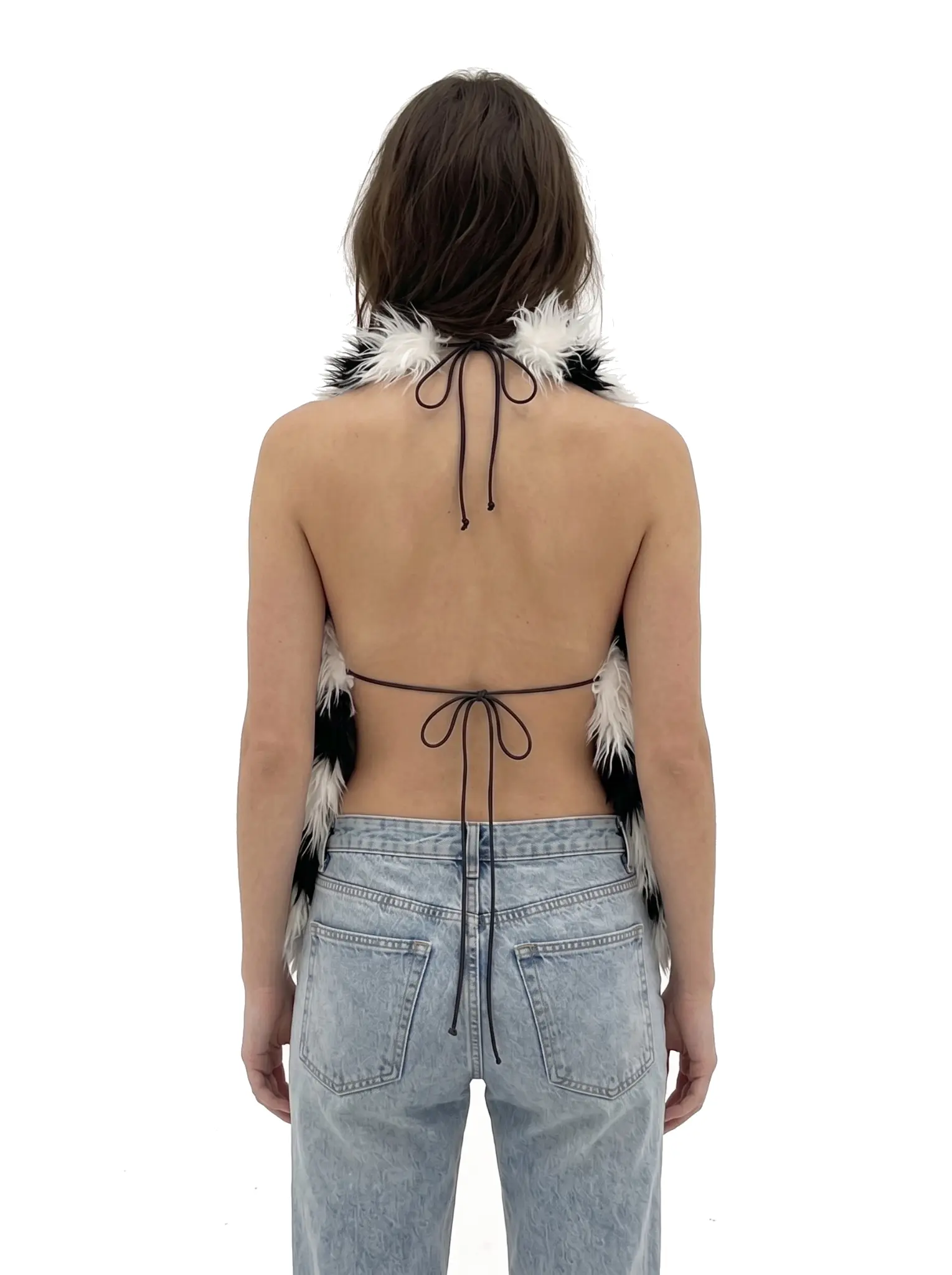 Back view of a woman wearing a spotted faux fur halter vest with adjustable tie straps
