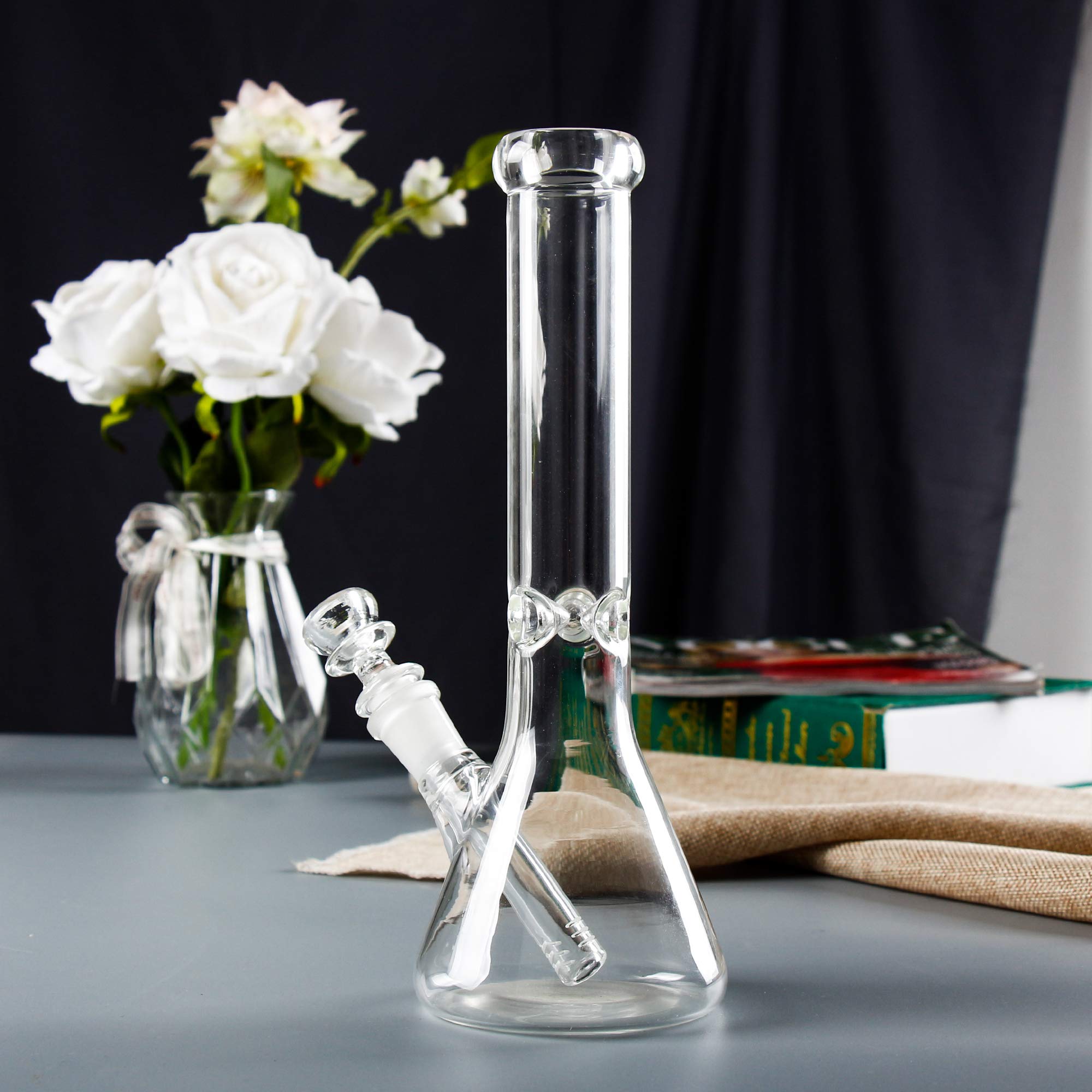 Clear beaker glass bong with ice pinch and 14mm bowl on a blue-grey tabletop with burlap