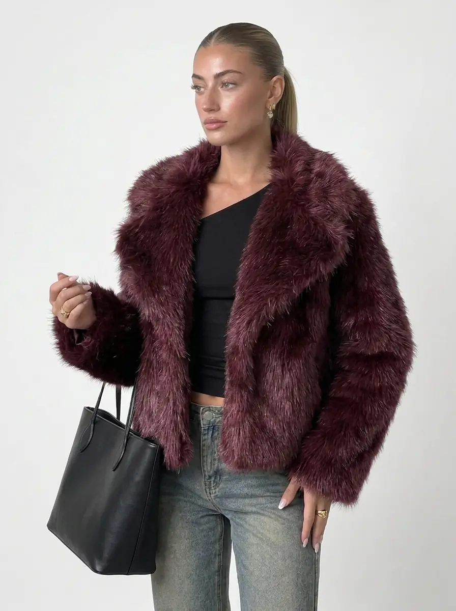 Woman wearing a maroon faux fur jacket in a three-quarter view