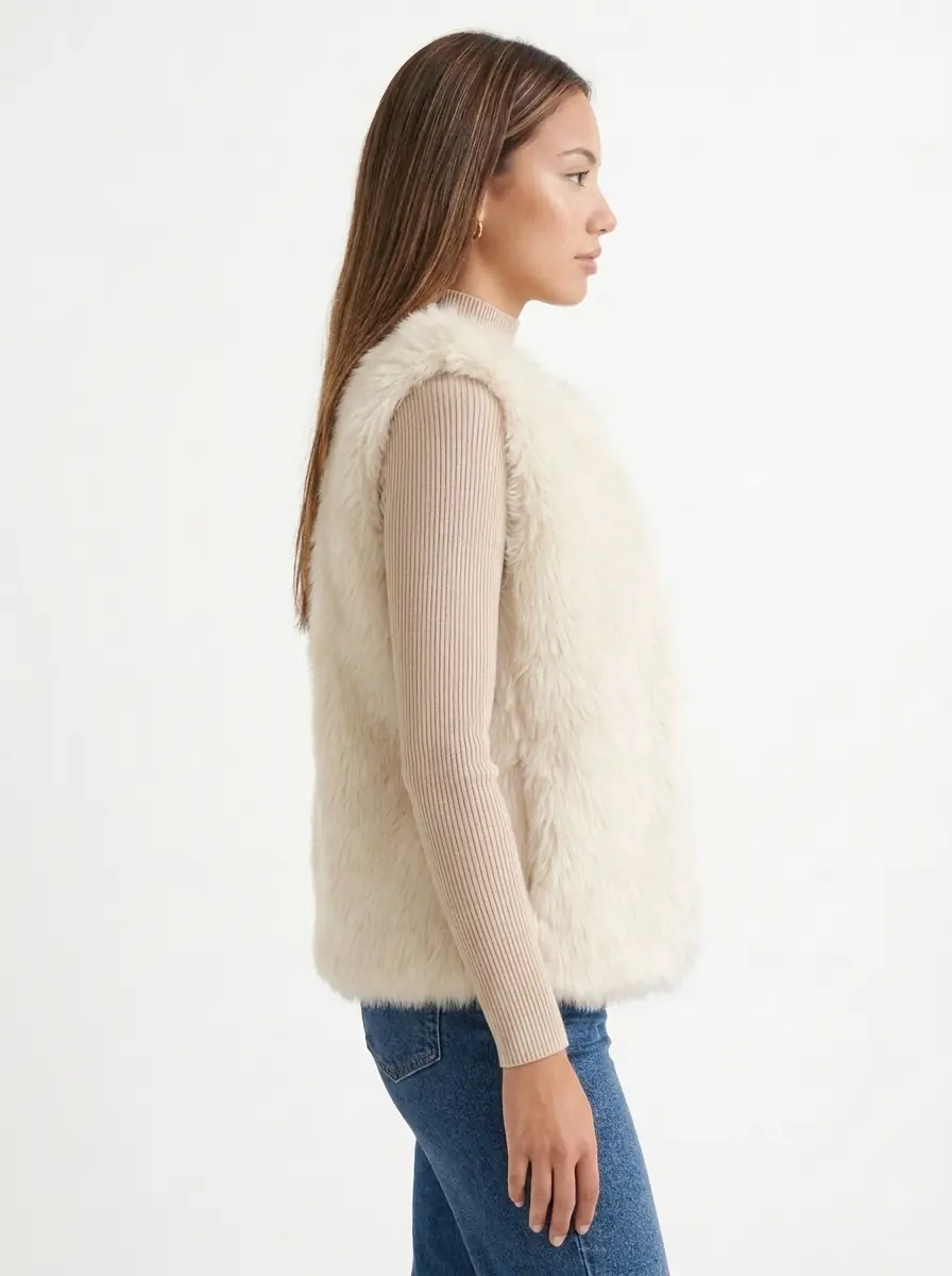 Side view of a woman wearing a cream faux fur vest