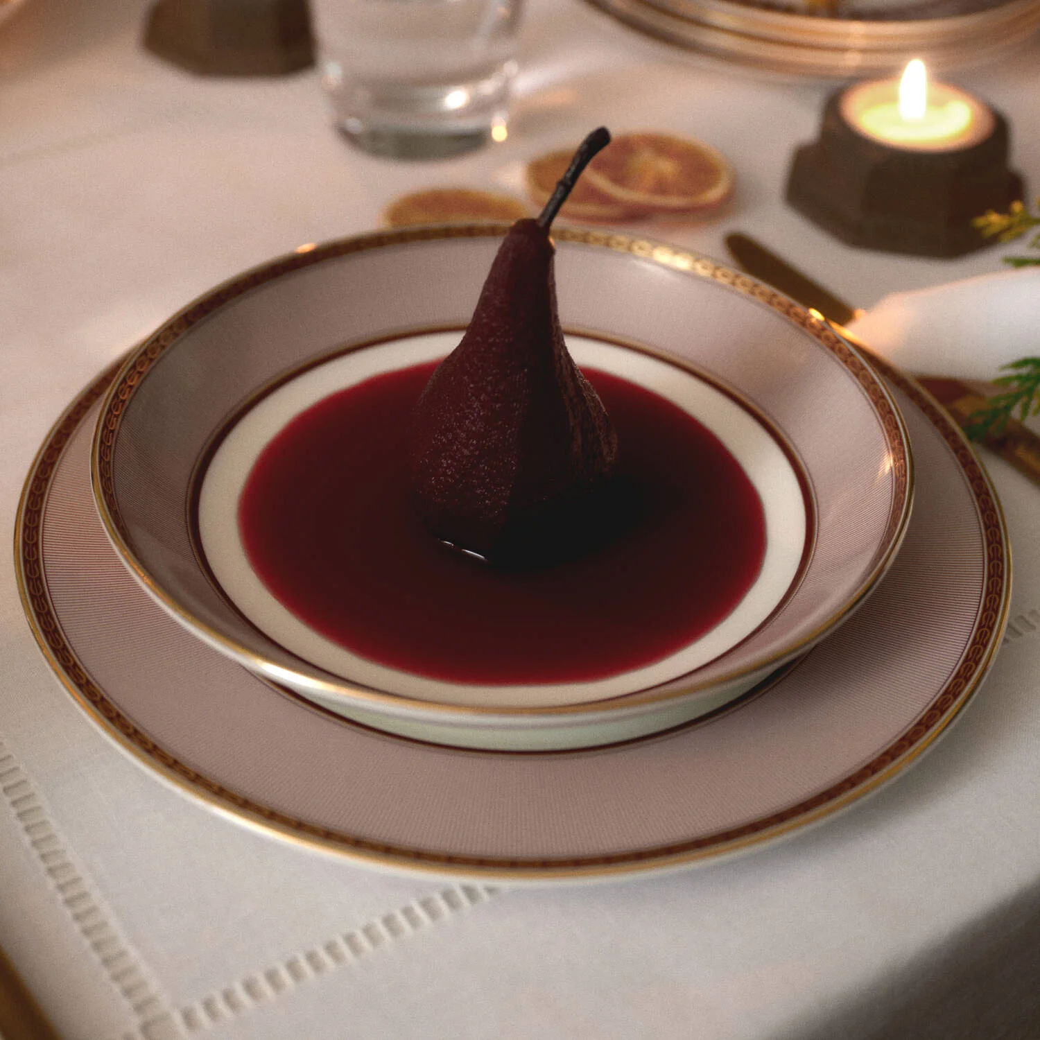 Splendour Red Deep Plate - A plated dessert in a Red Splendour bowl  featuring a dark red pear centered in a white bowl filled with deep red sauce, set on a beige and gold charger plate on a white tablecloth with a candle in the background.