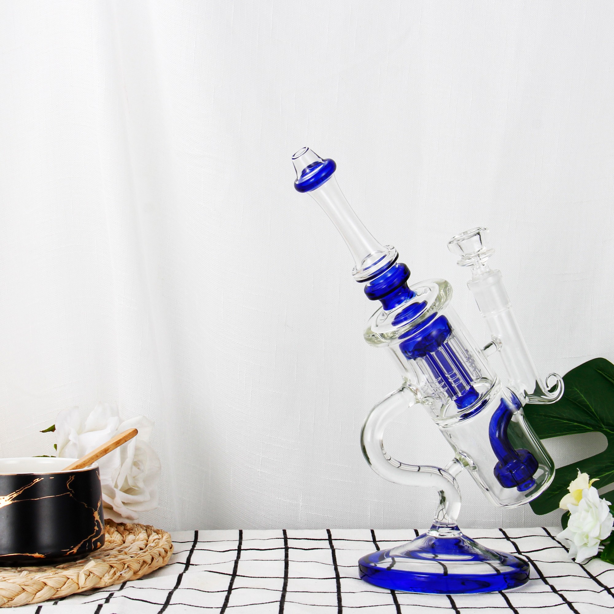 10-inch blue recycler bong on a table next to a marble cup and white flowers